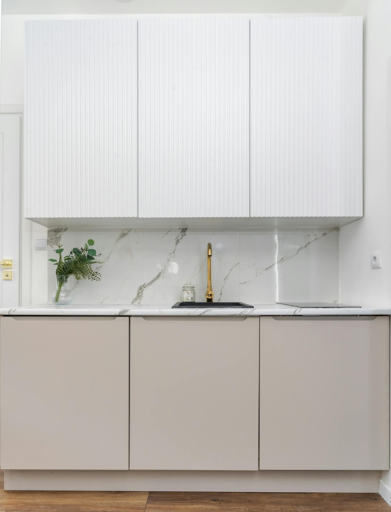 Moda'da bir konutta mermer tezgah, oluklu dolaplar ve pirinç bataryalı minimal bir mutfak